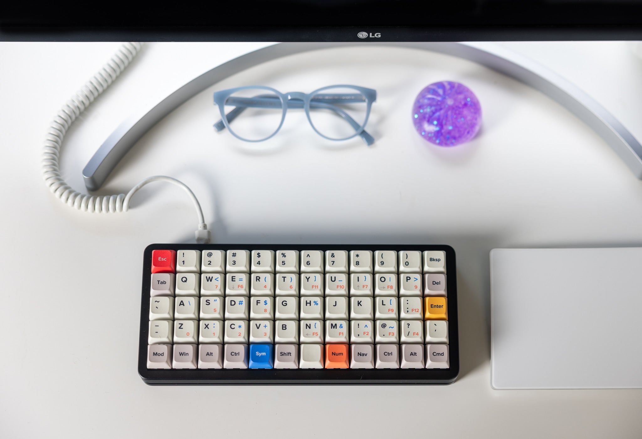 Preonic Rev 4 on a white desk with a coiled cable, glasses, and a monitor